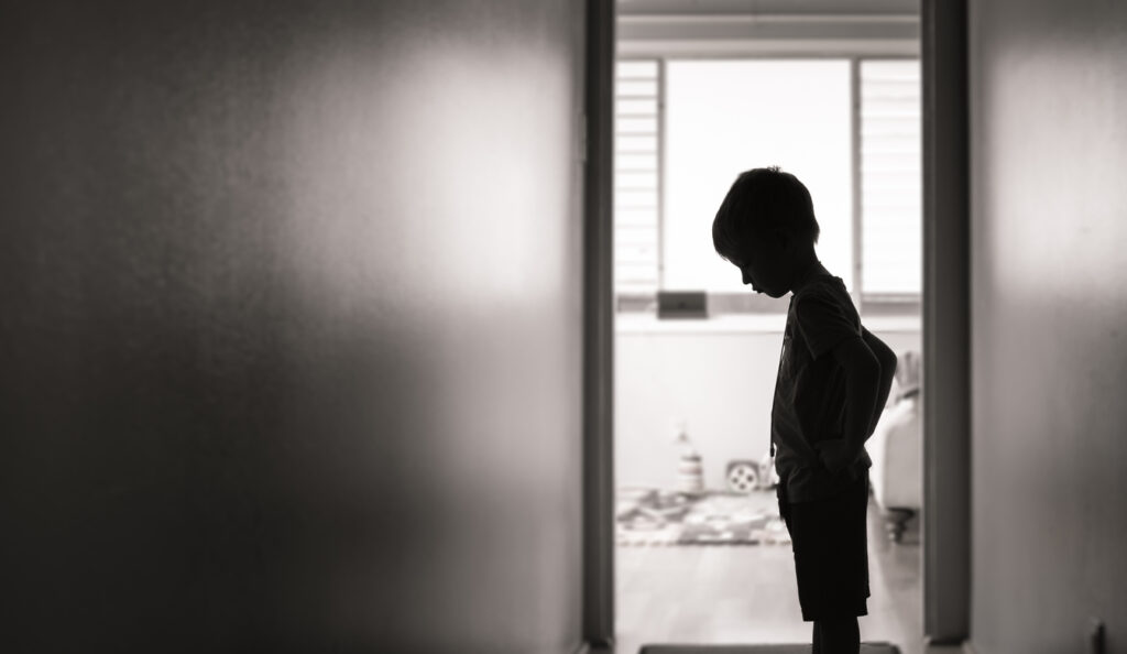 A sad boy standing in a hallway