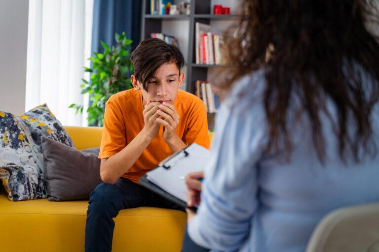 A minor sitting and thinking as he goes through a forensic interview conducted by a professional.