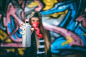 Woman pointing a spray can indicating a criminal mischief.