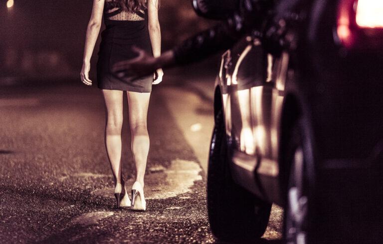 Woman standing in front of a car to suggest solicitation of prostitution.
