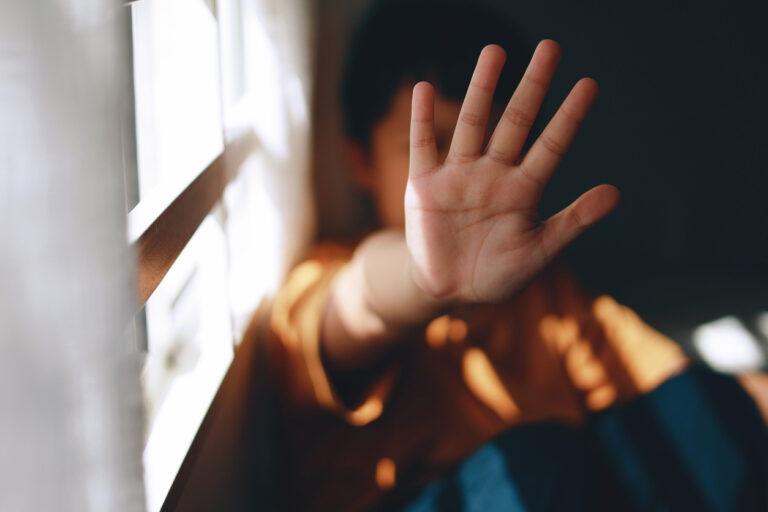 Young boy holding his palm open in a stop gesture showing signs of child pornography in Texas.