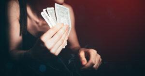 Woman lying on a bed with money on her hands suggesting solicitation of prostitution in TX.