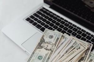 Stack of counterfeit U.S. dollar bills on a laptop keyboard, symbolizing digital financial fraud.