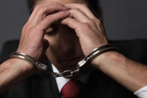 Man in a suit handcuffed and stressed, representing arrest for deep fake pornography