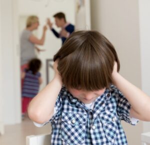Child covering ears while parents argue in the background, representing the impact of family violence in Texas.