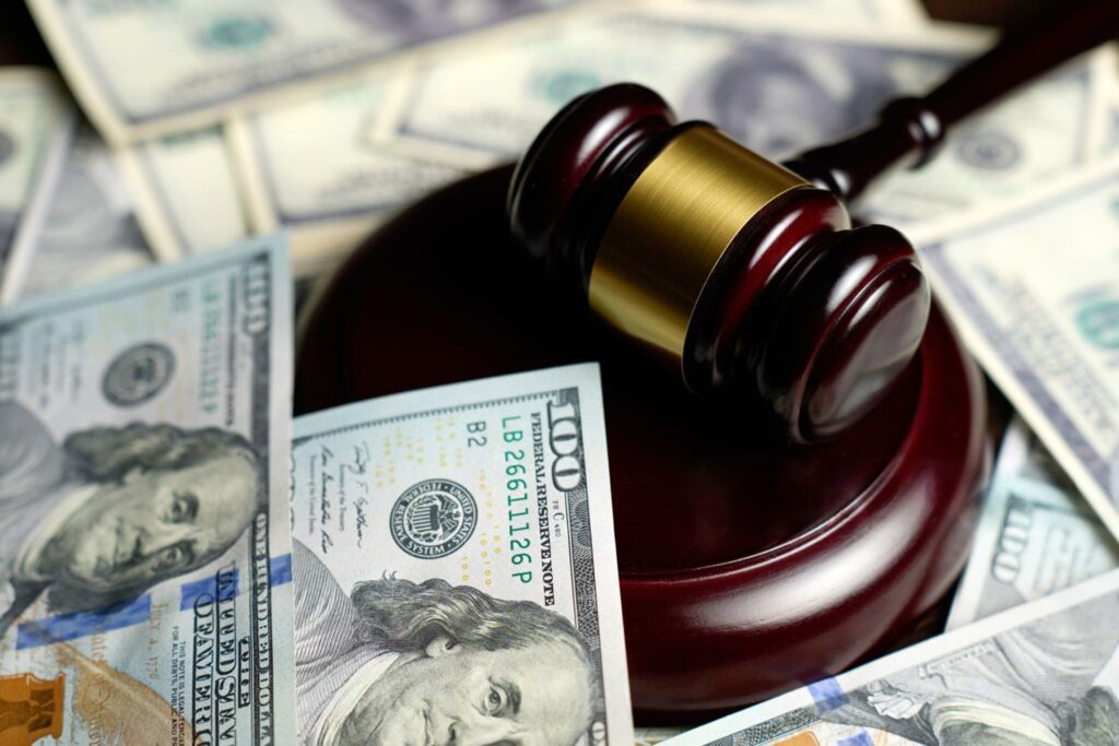 A stack of cash next to a judge's gavel, symbolizing the cost of bail versus the power of legal defense.