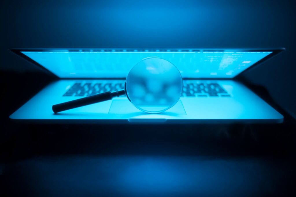 A laptop with a magnifying glass, symbolizing the digital forensics used in child exploitation investigations.