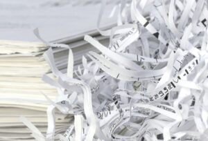 A person's hands feeding a criminal record document into a shredder.