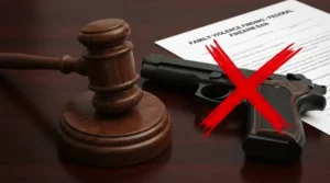 A judge's gavel next to a crossed-out firearm, symbolizing the lifetime gun ban from family violence findings.