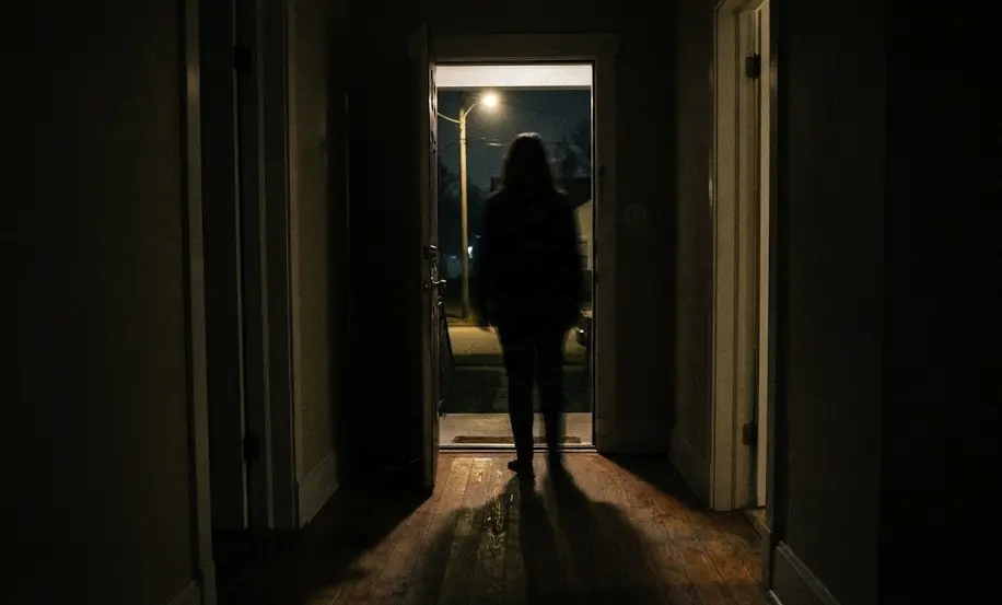 A shadowy figure standing in a doorway, symbolizing intimidation and fear in family violence cases.